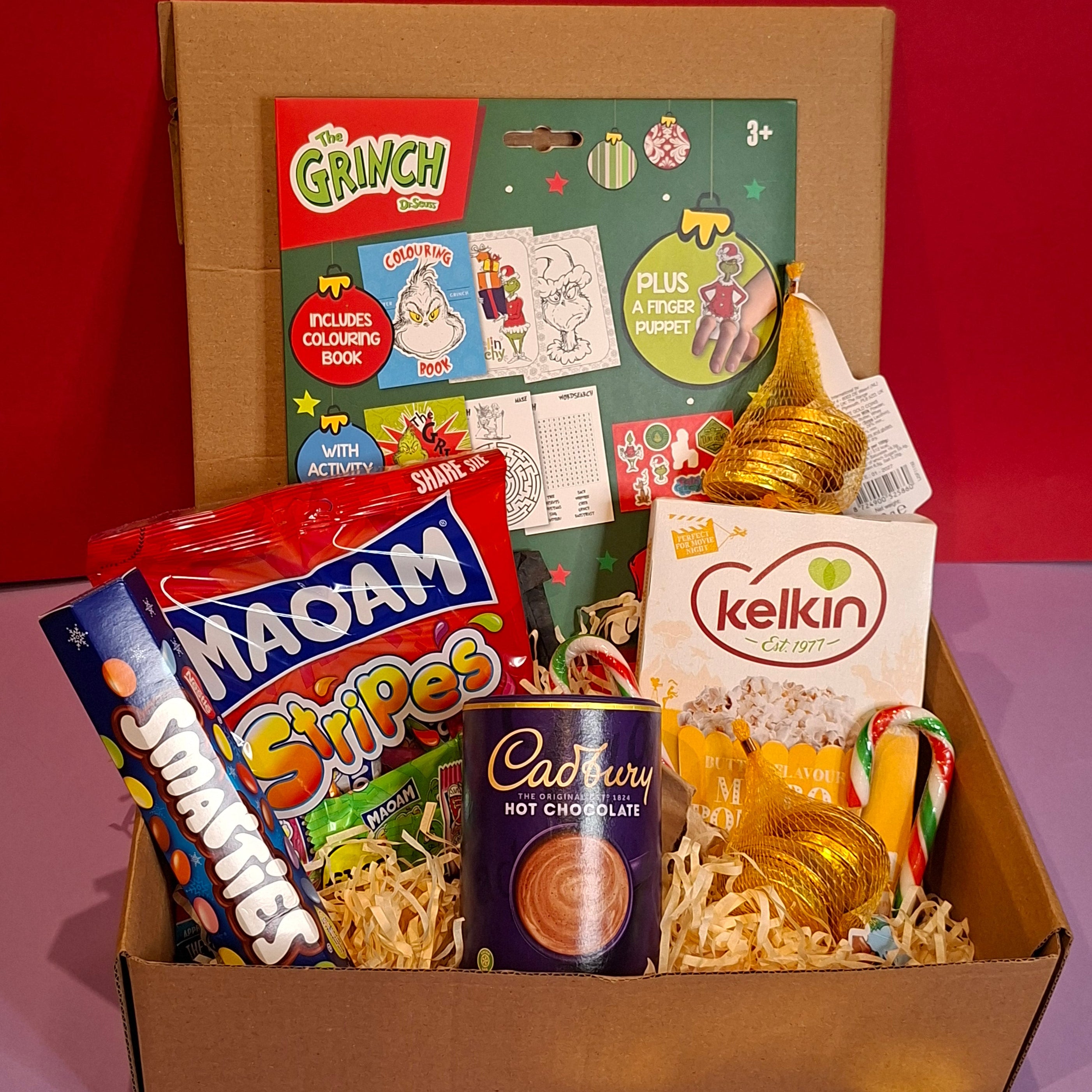 Toy Show gift box Ireland featuring festive treats, candy canes, popcorn, sweets, and hot chocolate in a Christmas hamper